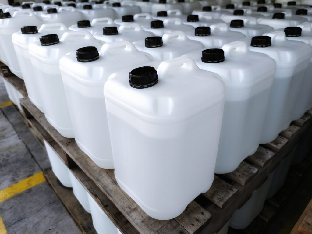 White plastic drums (20kg) stacked on a wooden pallet. Chemical packaging materials